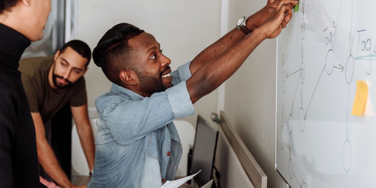 A team or individuals collaborating around a whiteboard, representing strategic planning and problem-solving to avoid business pitfalls.