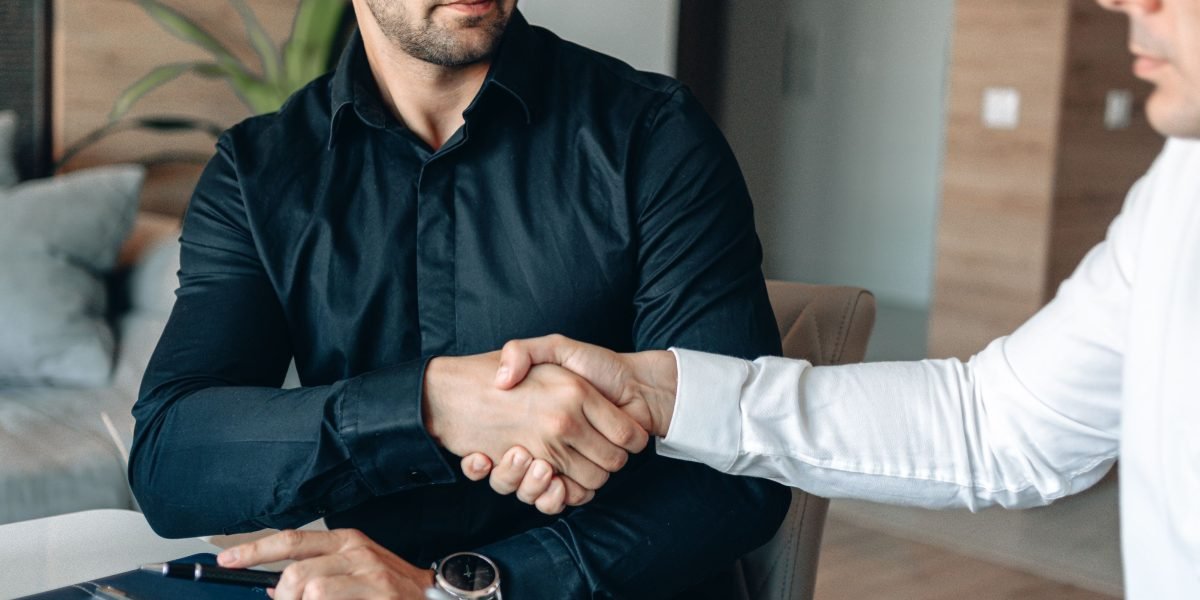 Two business partners shaking hands after finalizing an agreement, symbolizing the signing of a contract with a tax advisor.